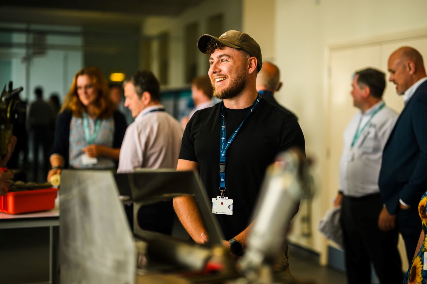 1 person in focus smiling in a room full of other people out of focus